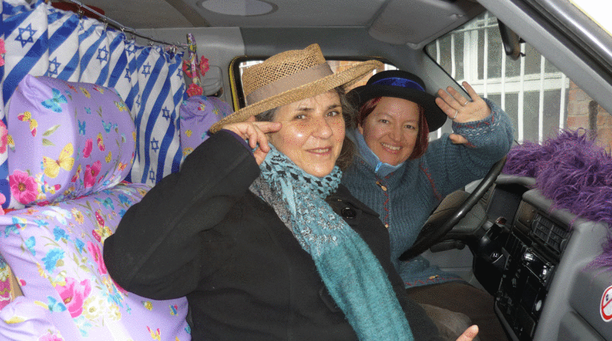 Zwei Frauen sitzen winkend in einem Bus.