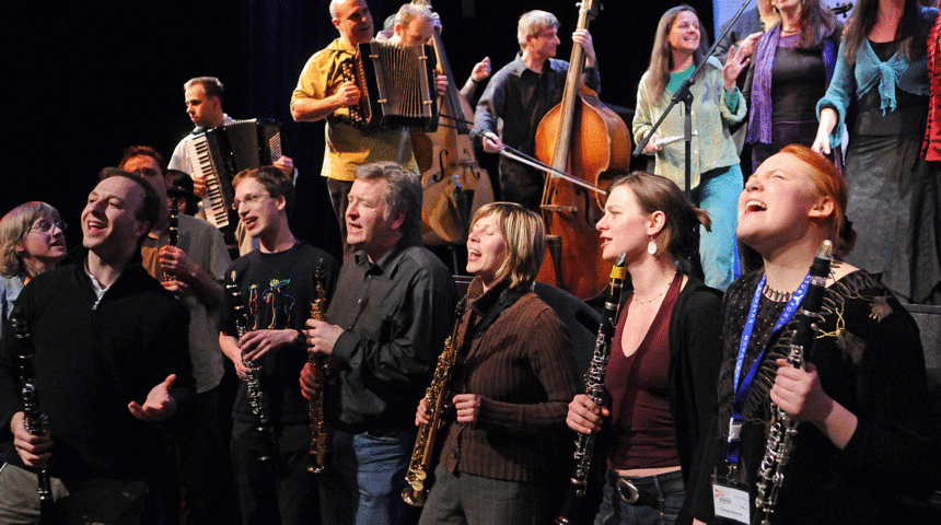Hobby-Musikerinnen und Musiker mit Instrumenten singen und spielen auf der Bühne