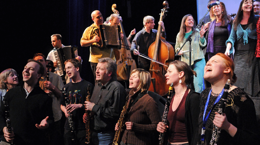 Hobby-Musikerinnen und Musiker mit Instrumenten singen und spielen auf der Bühne